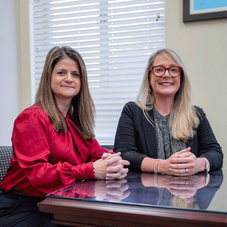 Lumi Bakos and Emily Devereux sit at a table in a conference room