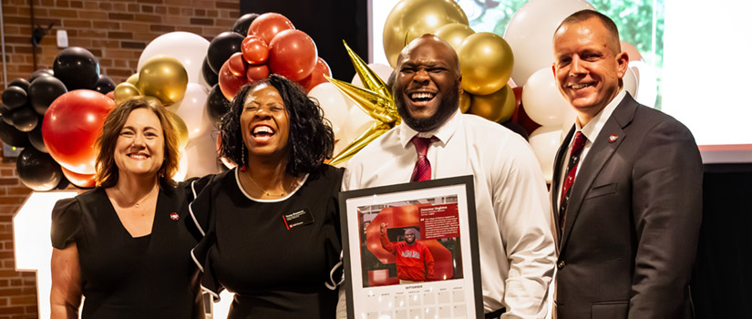 Laughing group of people, one holding framed calendar page