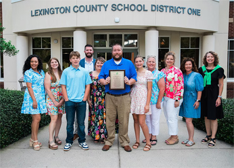 Group of teachers, Albert Robinson holding a plaque at center