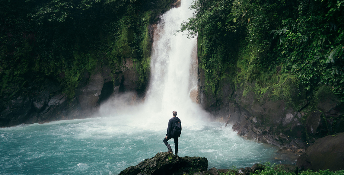 Person standing in front of a large waterfall in Costa Rica