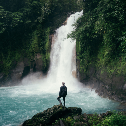 Person standing in front of a large waterfall in Costa Rica