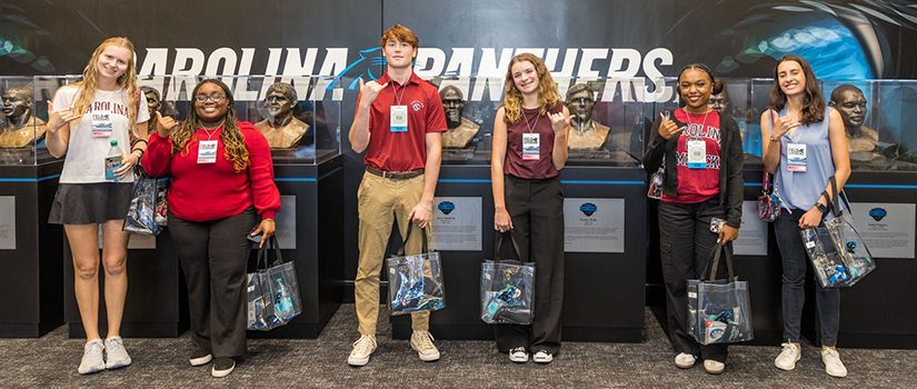 Cohort 5 Tepper Scholars throw up a Spurs Up hand sign while visiting the Carolina Panthers' stadium.