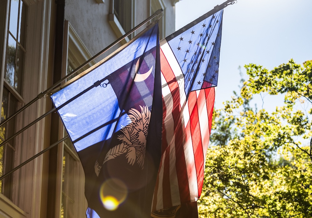 south carolina and american flag hanging next to beige building