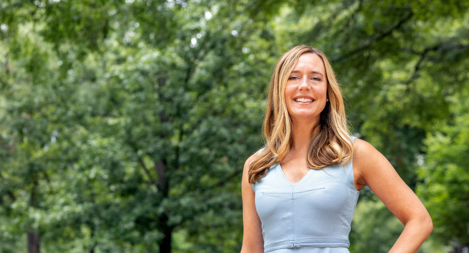 woman stands outdoors with greenery in the background