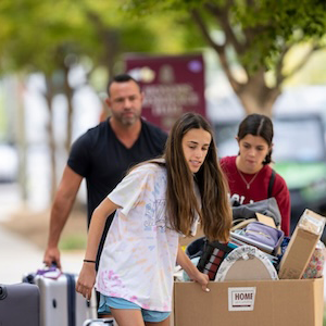 girl pulling box full of move-in items in a rolling cardboard box