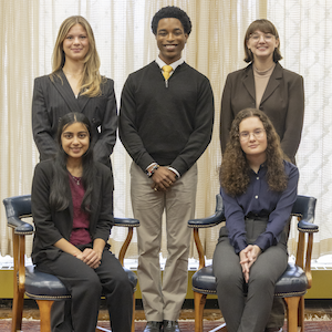 group of people together in front of a window with three standing and two sitting
