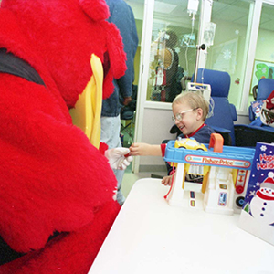 Cocky interacts with a small child in a hospital setting.