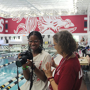 Female instructor helping a female student with a film camera. 